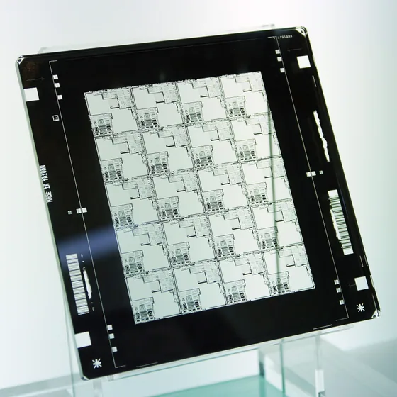 A chrome-on-glass semiconductor photomask — a quartz plate carrying an array of identical circuit patterns with alignment marks, the fixed template a mask aligner projects onto the wafer